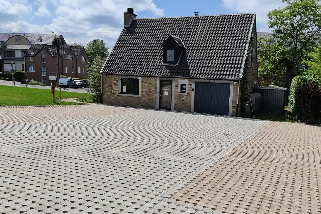 Pavés drainants rustiques - Cendre et Luxembourg - 14,5 x 14,5 x 6 cm Grande cour en pavés drainants devant une maison en pierre avec un toit en ardoise