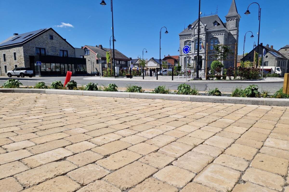Allée en pavés carrossables carrés et rectangles devant une place de village.
