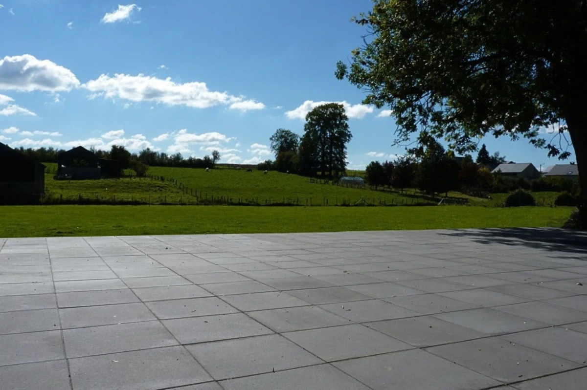 Terrasse en dalles béton bordant un jardin en campagne