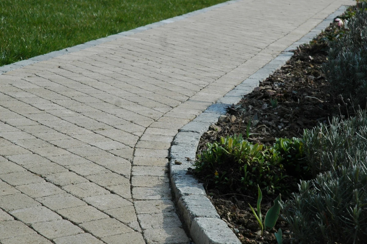 pave-exterieur-hiver Allée de pavés rustiques bordée d'herbe et d'un espace de plantation.