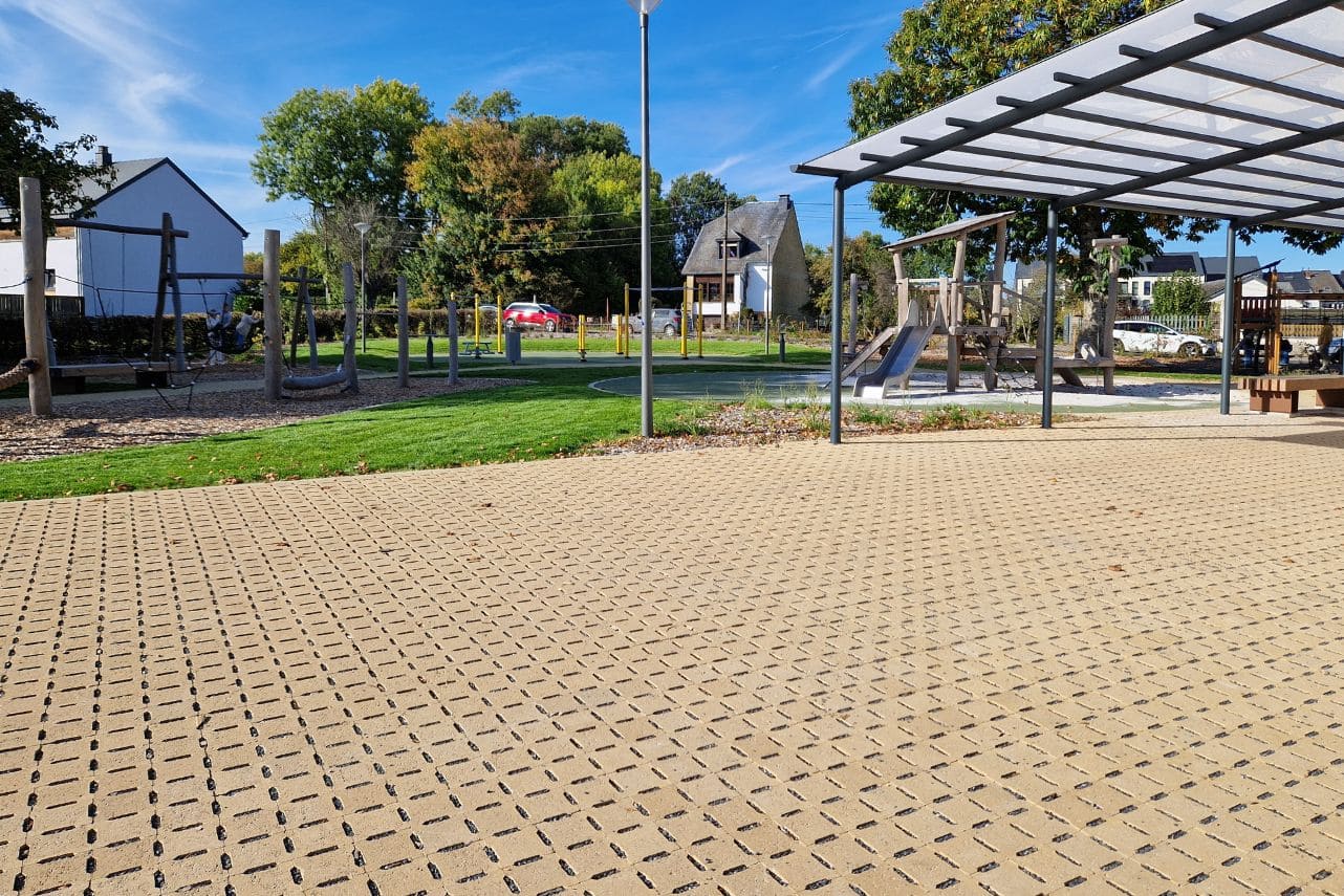 Pavés drainants - Luxembourg - 14,5 x 14,5 x 8 cm Pavés drainants bordant un parc avec une plaine de jeux