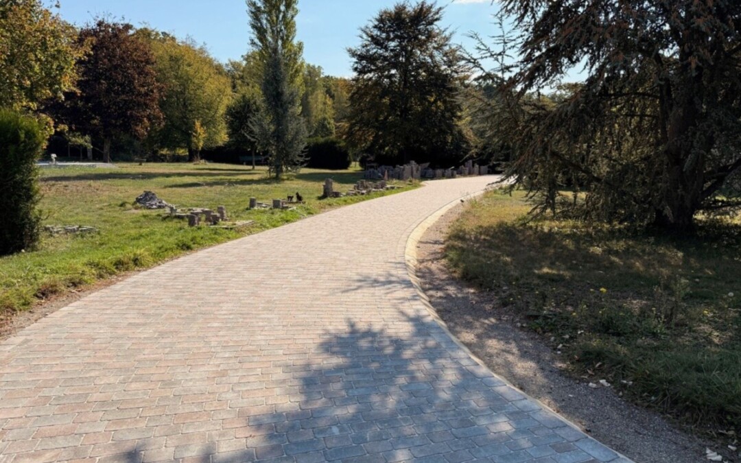 Allée pavée dans les ton gris et bruns. L'allée est bordée d'arbres et de végétation.